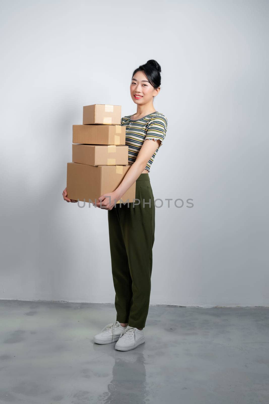 Happy asian woman holding pile of boxes, concept of delivery, shopping or business, white background by makidotvn