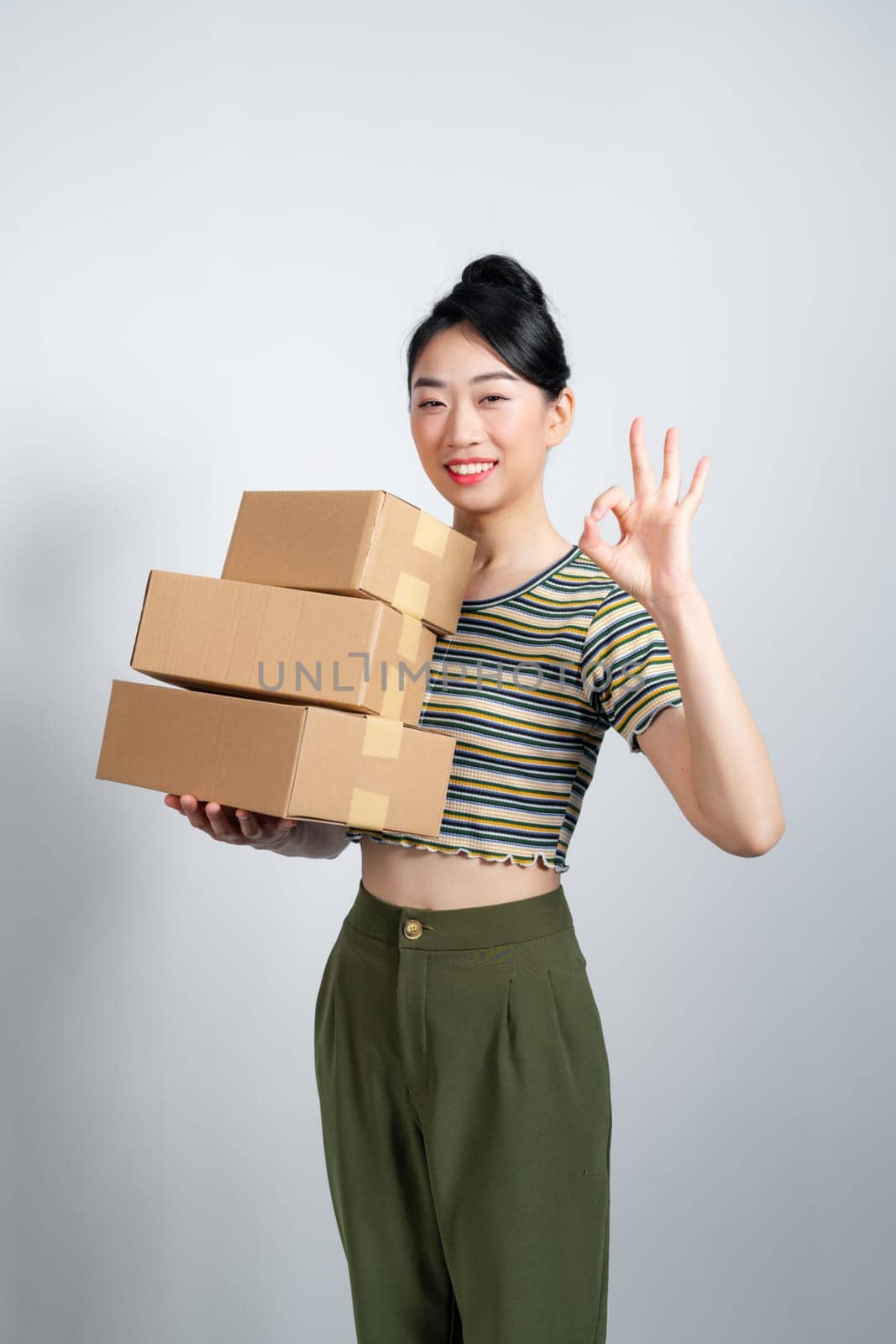 Portrait of young Asian business woman with boxes showing OK sign by makidotvn