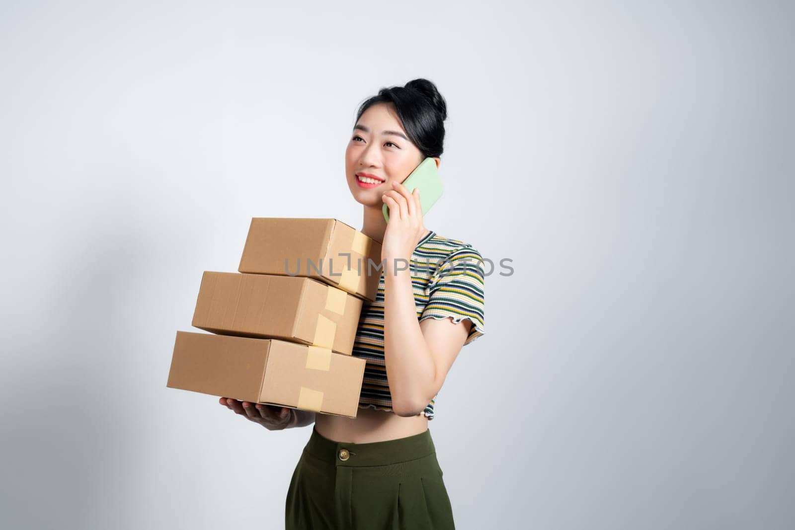 woman carrying cardboard box stack and talking on the mobile phone