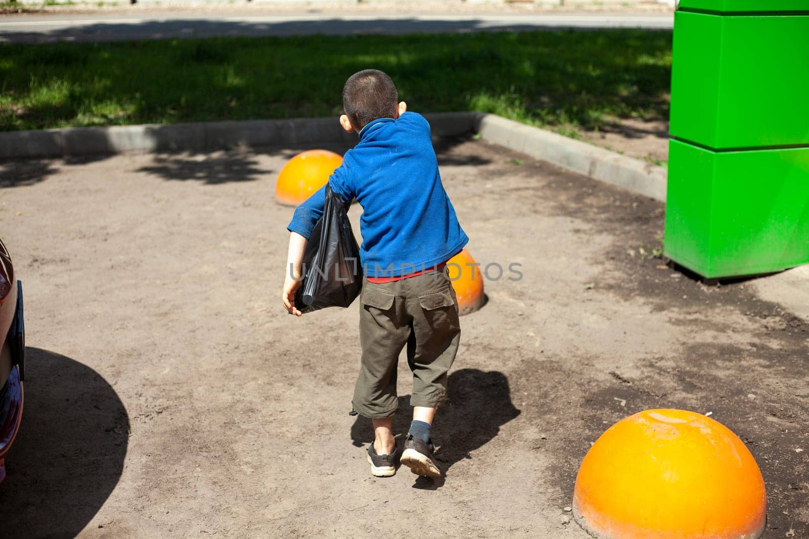 Child carries bag down street. Independent child comes from store with groceries. Boy is alone on street. Kids in town.