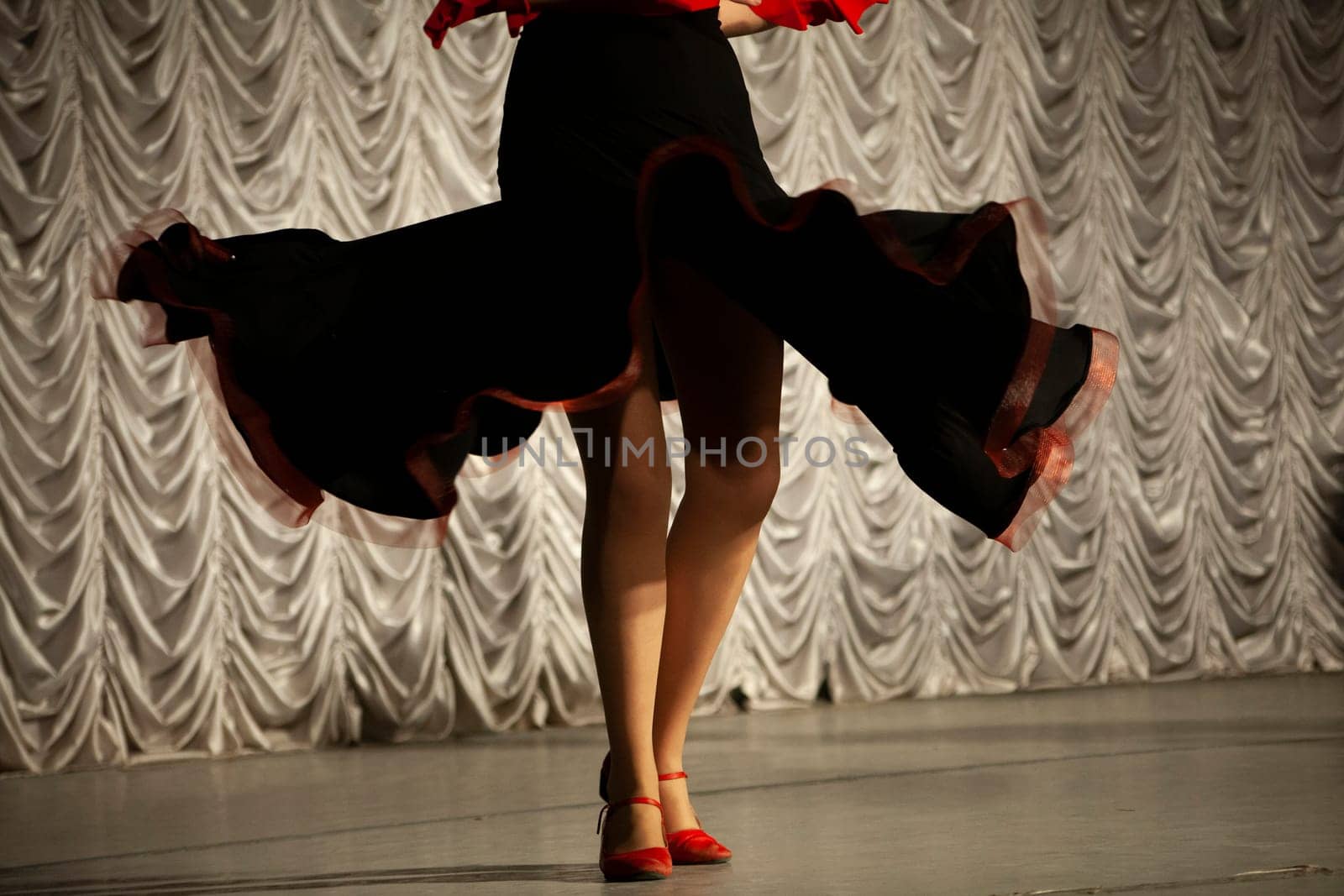 Spanish dance. Black dress. Dancer on stage. Details of speech. Incendiary movement. Beautiful girl spinning in long dress.