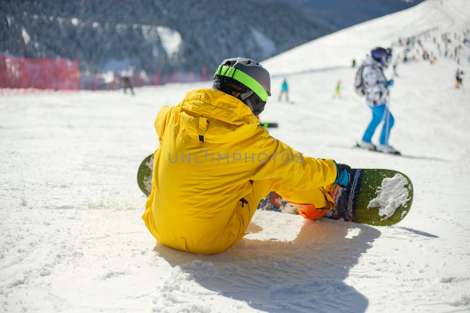 A snowboarder rides on a slope. Rest on the top of the mountain. Mountain ski resort. The guy is rolling down the mountain. Hobbies for young people. Holidays in the winter on a slope for snowboarding.