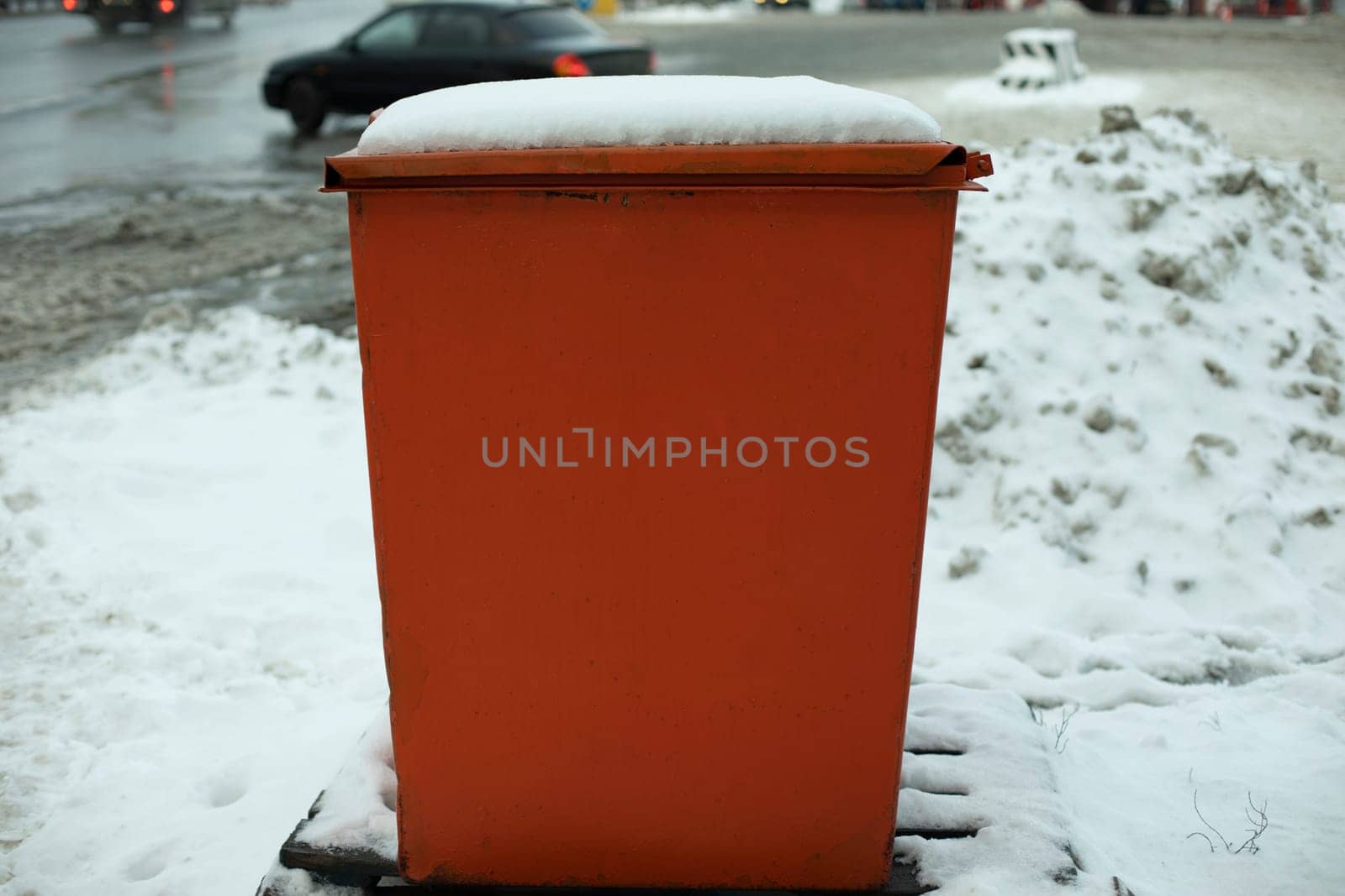 Steel tank. Dumpster. Place to store sand on highway. Orange object in winter on road. by OlegKopyov