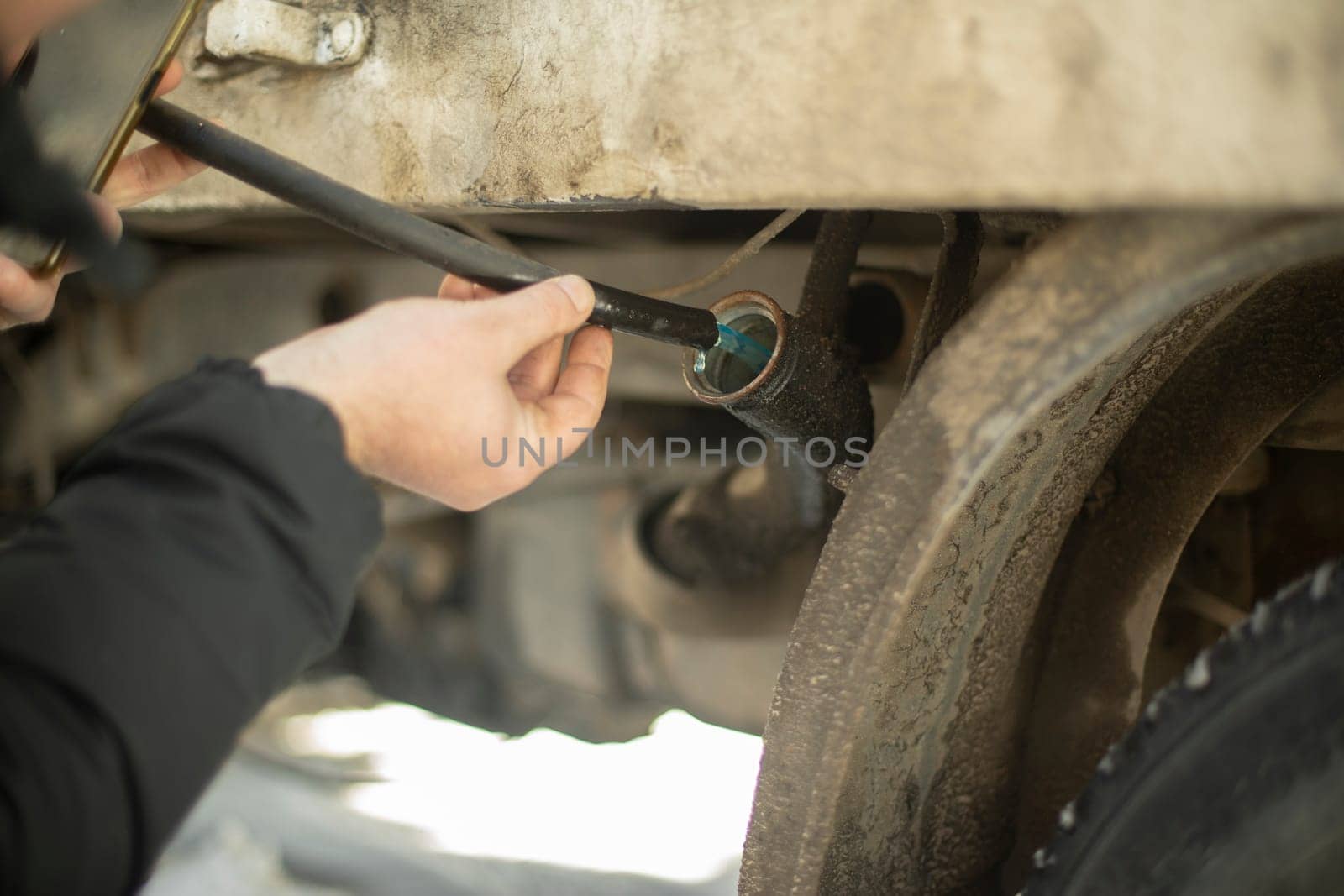 Guy drains fuel from car. Pumping gasoline. Hands hold hose with fuel. Theft of diesel from transport.