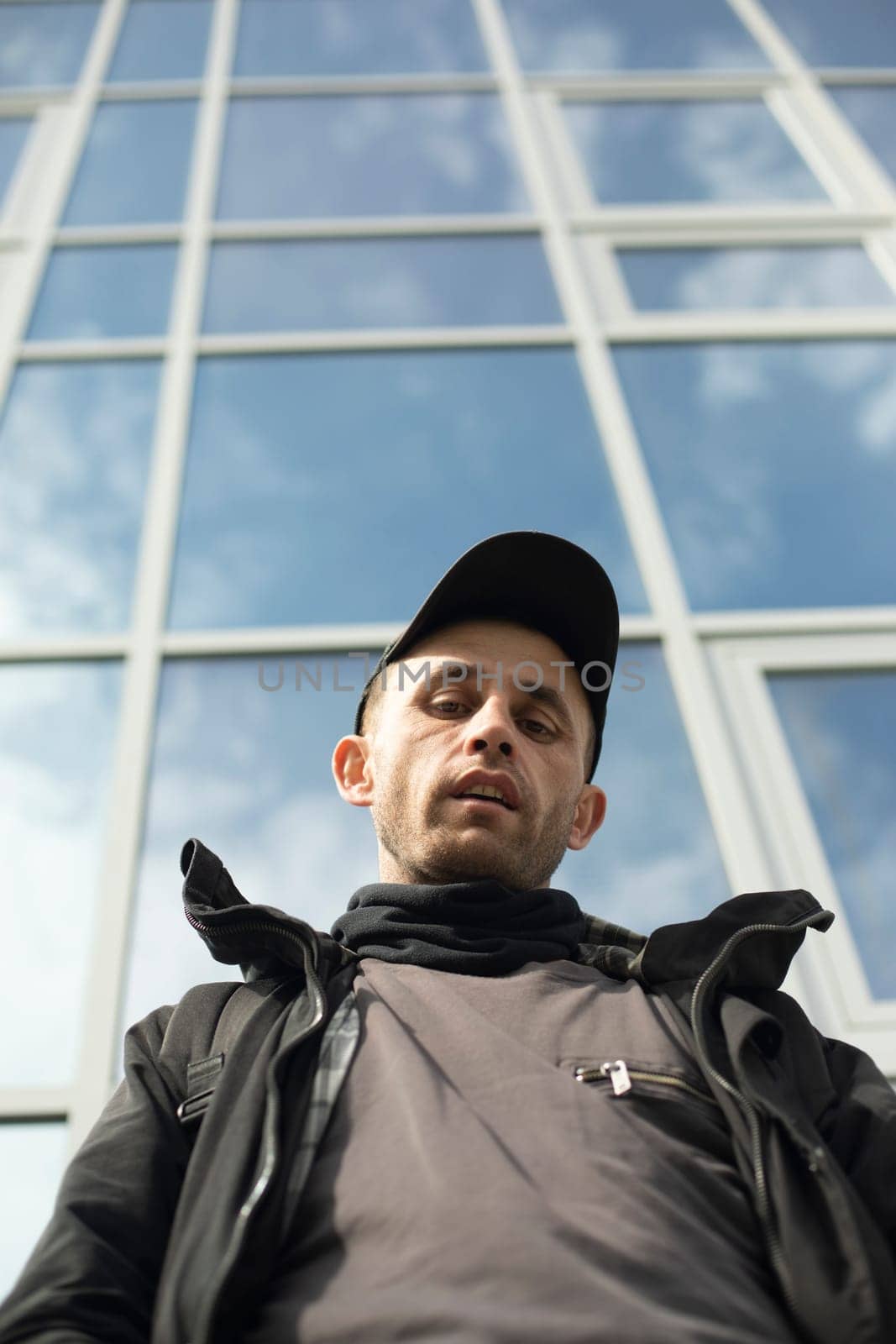 Guy in background of glass building. Man in cap. by OlegKopyov