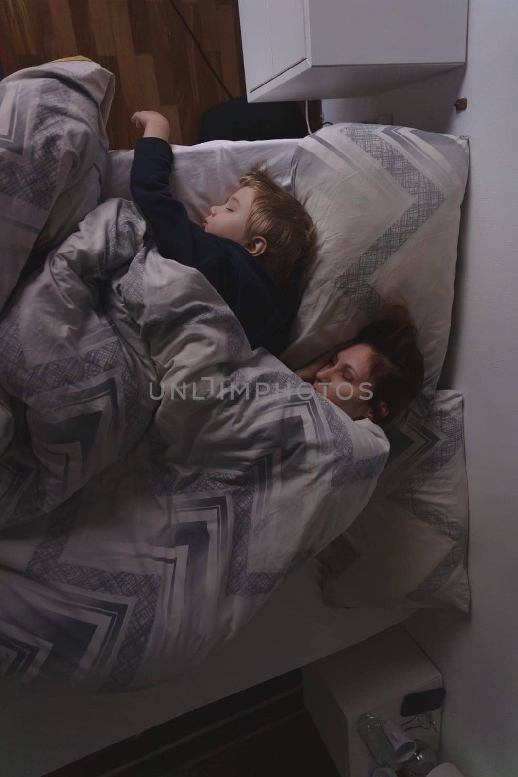 A mammy and three years old little son is sleeping in the bed - top view