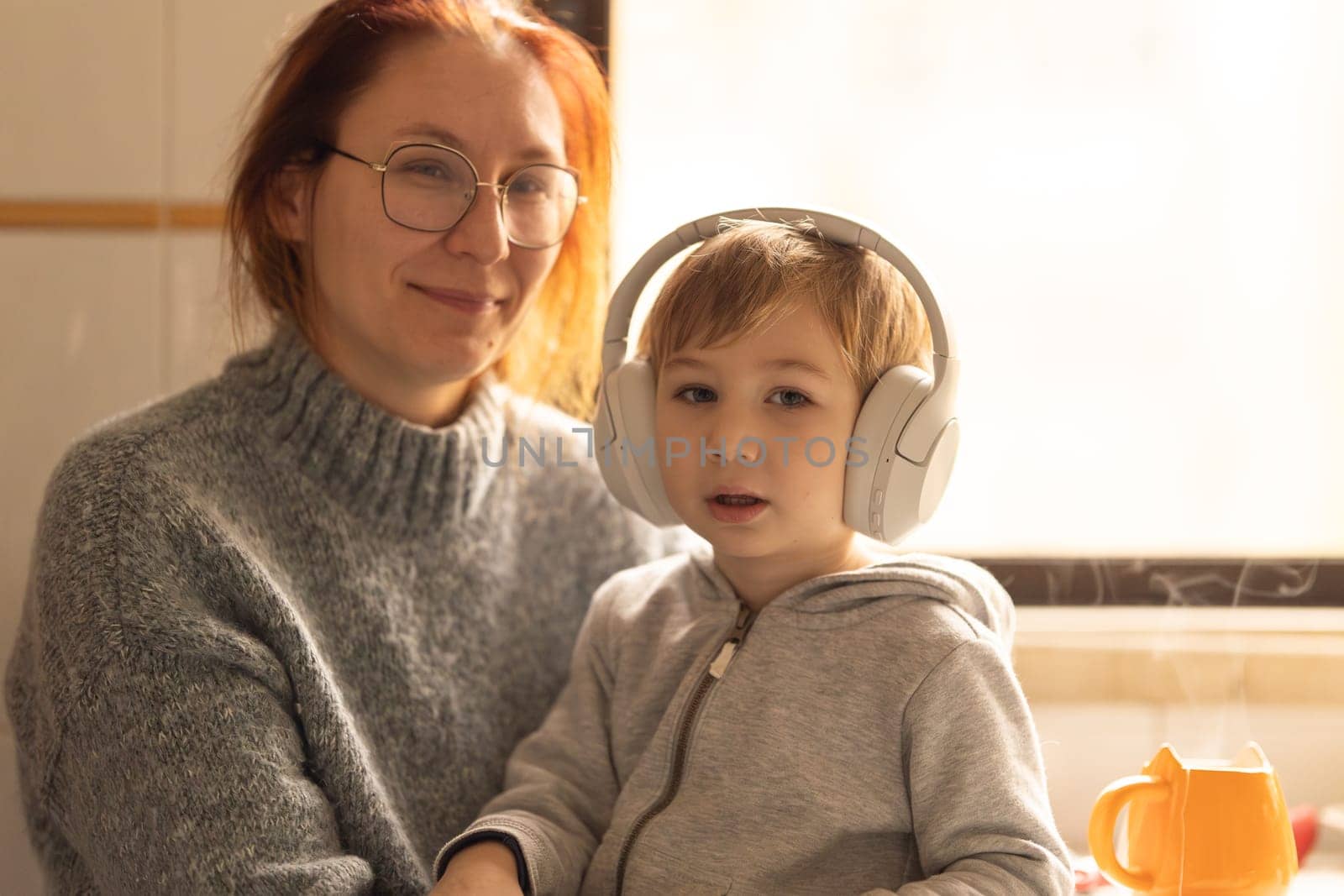 A woman and a child wearing headphones in a kitchen