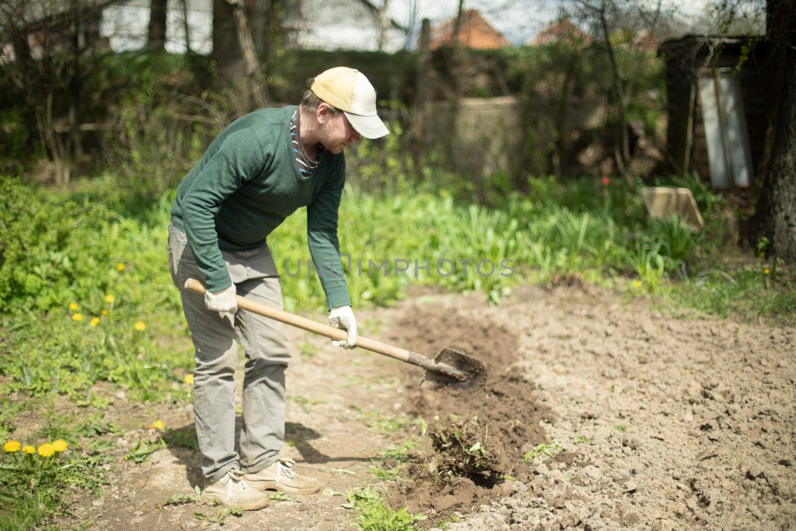 Guy digs soil with shovel. Digging up ground for planting. Work in garden. Life in countryside. Man works.