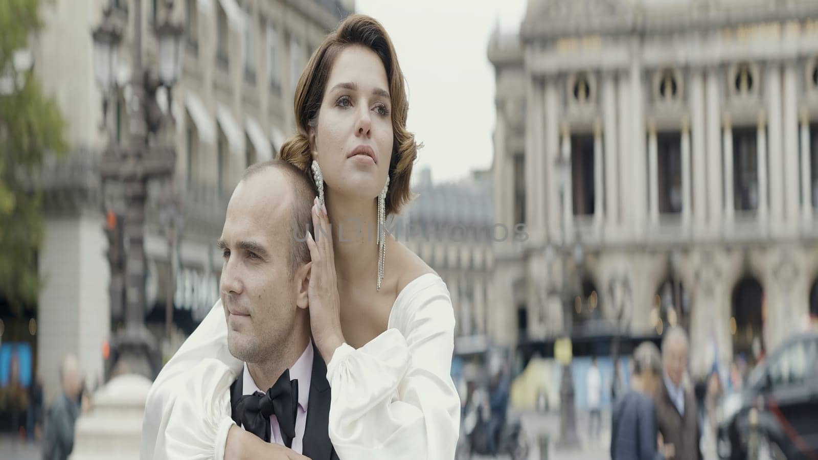 A man picks up his wife in his arms. Action. A date on the street where a girl in a white dress with a beautiful styling who jumps on her hands on a man in a suit in the fresh air. High quality 4k footage