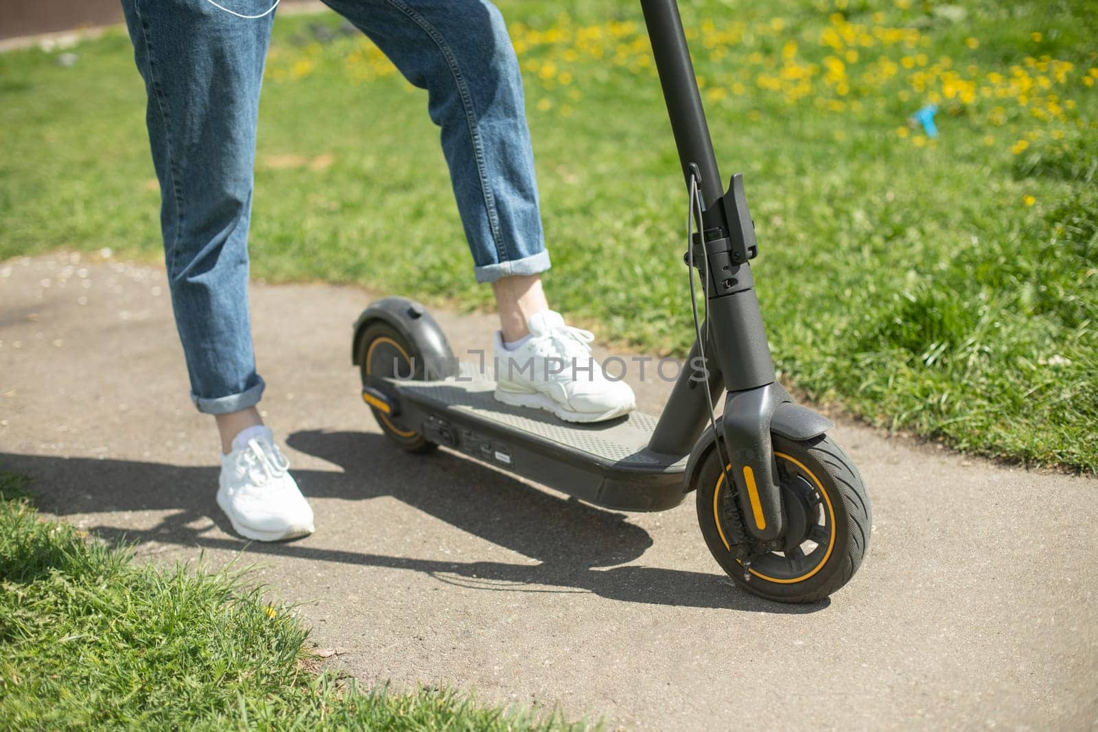 Guy on electric scooter. Man put his foot on platform of scooter. Electric transport in park.