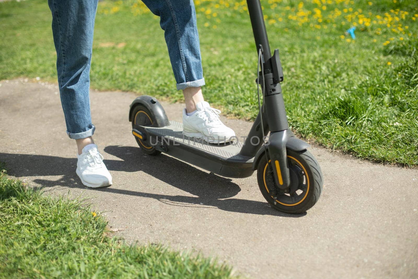 Guy on electric scooter. Man put his foot on platform of scooter. Electric transport in park.