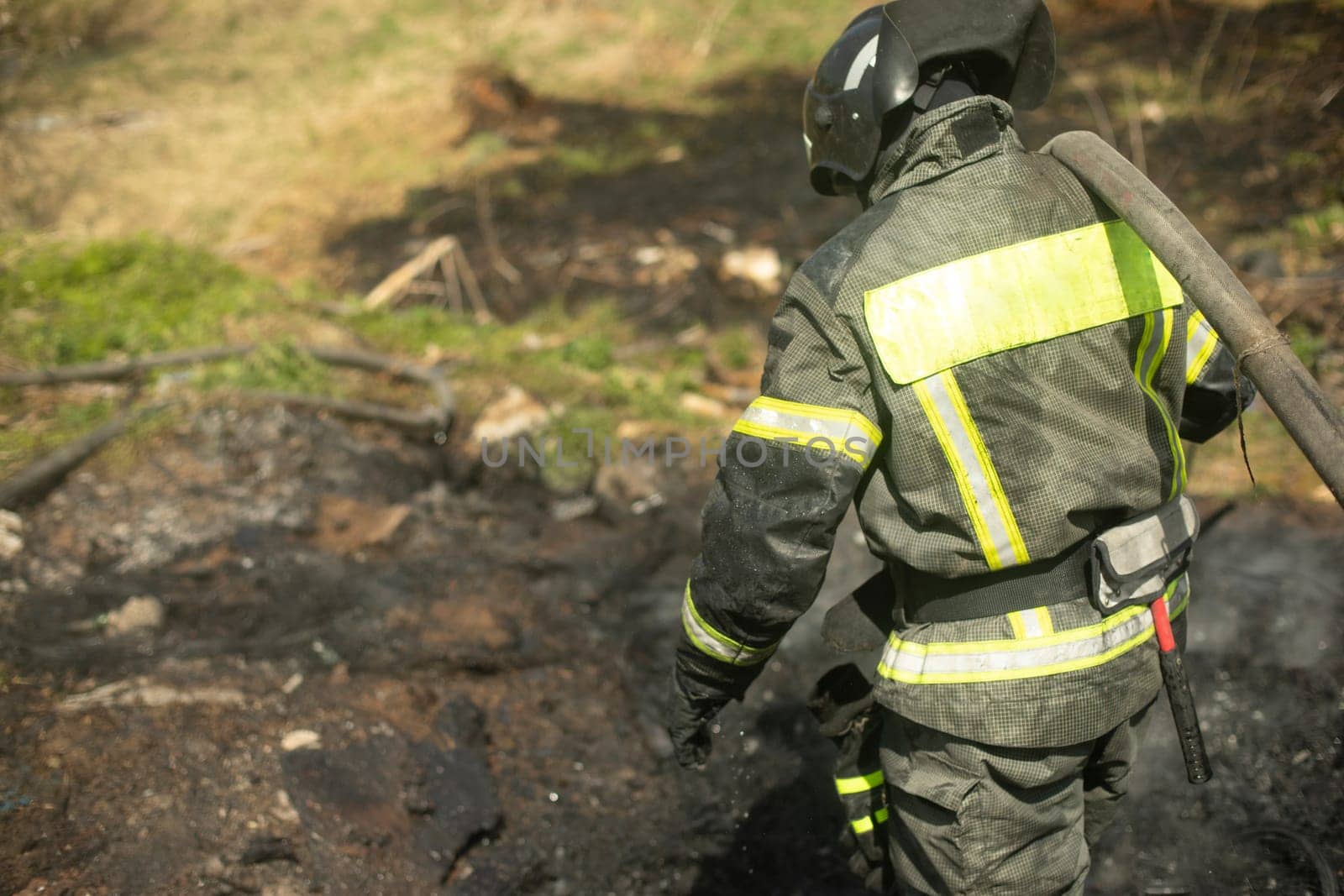 Firefighter puts out fire. Lifeguard pours water from hose. by OlegKopyov