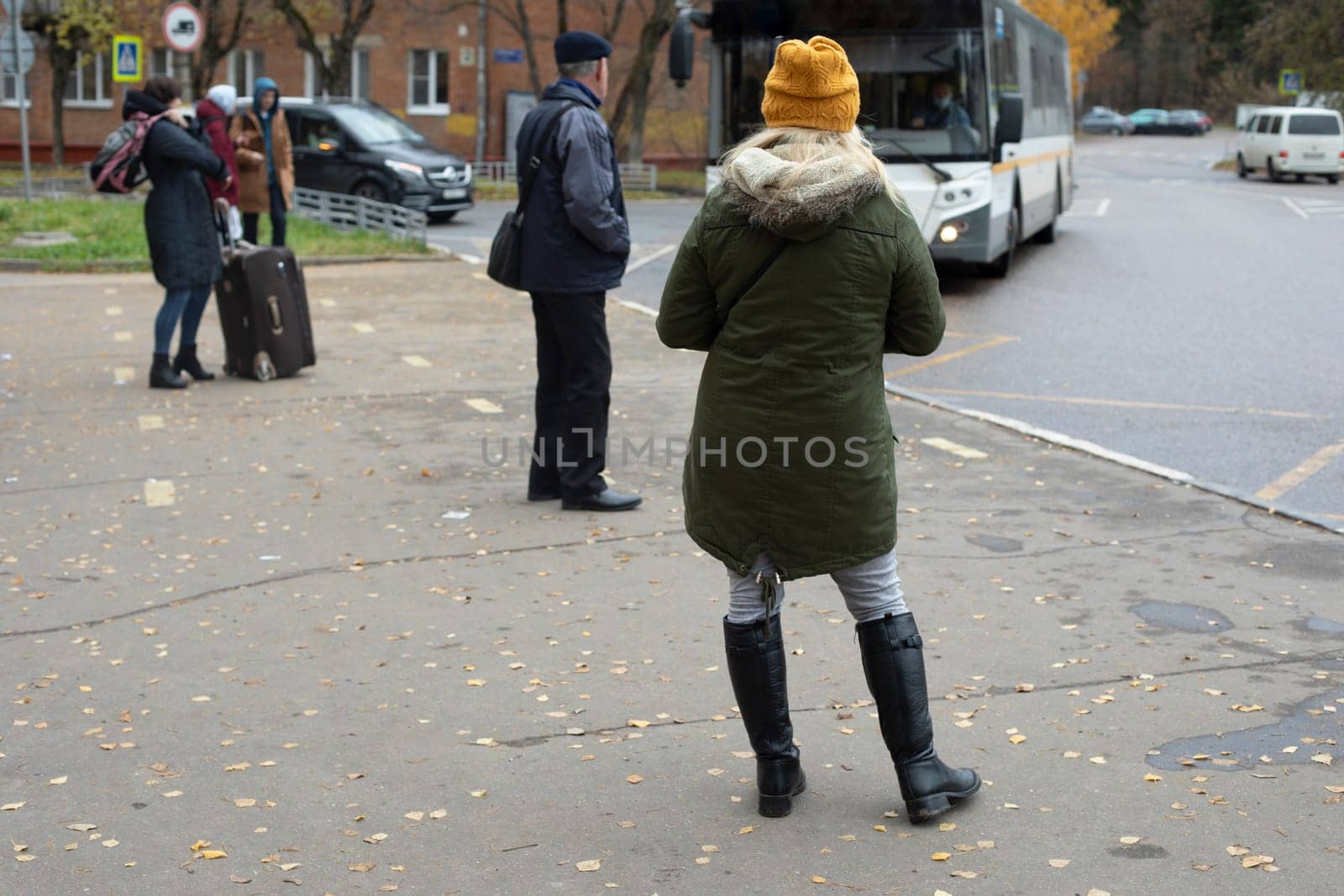 People are waiting for bus in fall. People at bus station. Public transport in city. People at bus stop. by OlegKopyov