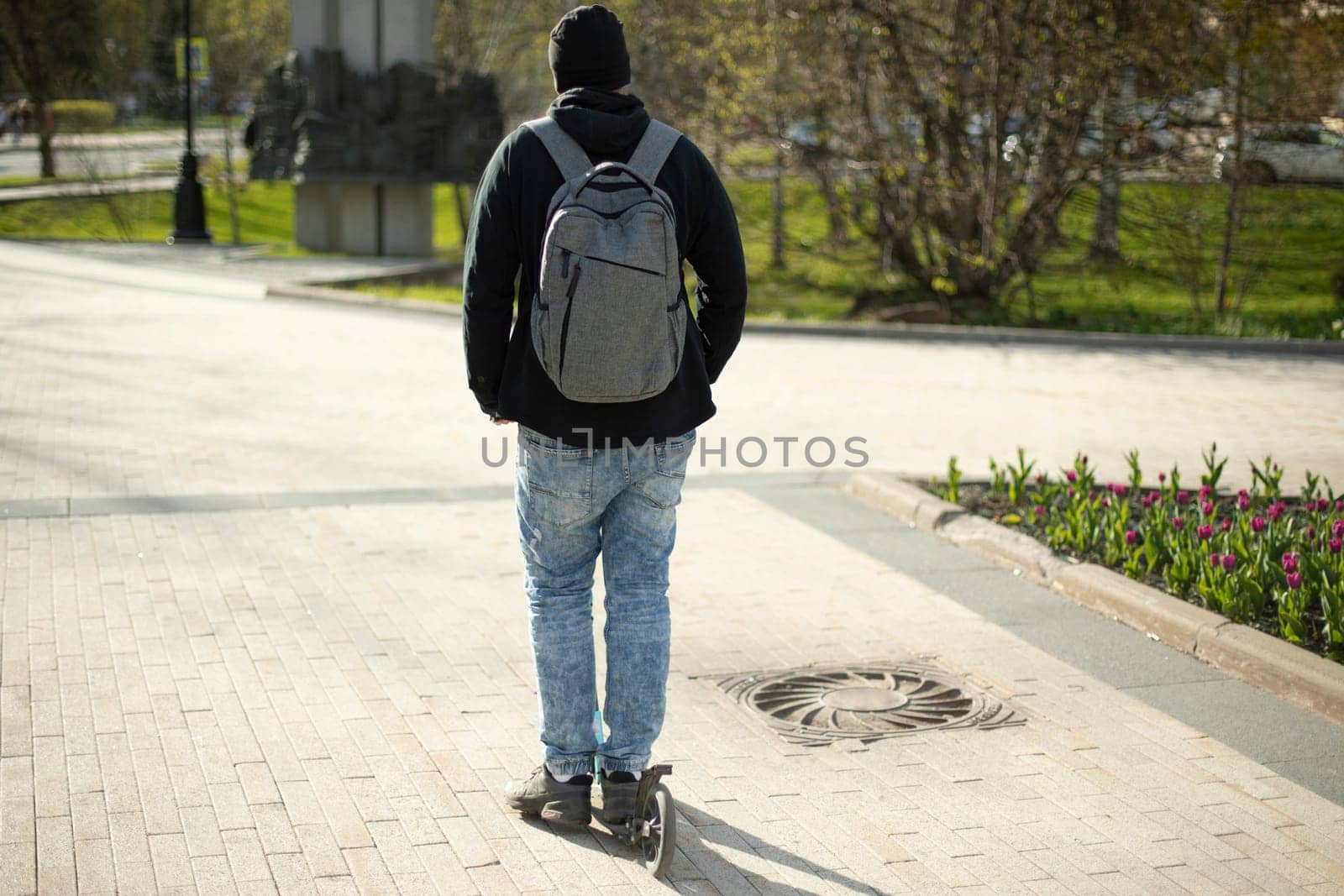 Guy rides scooter, guy rides around town on scooter. Man with backpack on street.