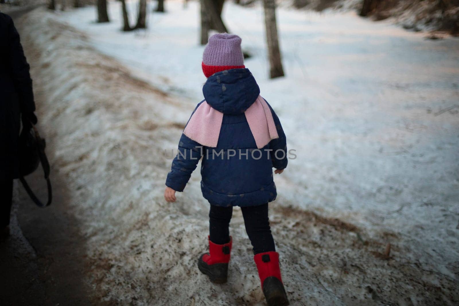 Child in warm clothes. Preschooler walks alone. Child walks down street. Children in urban environment.