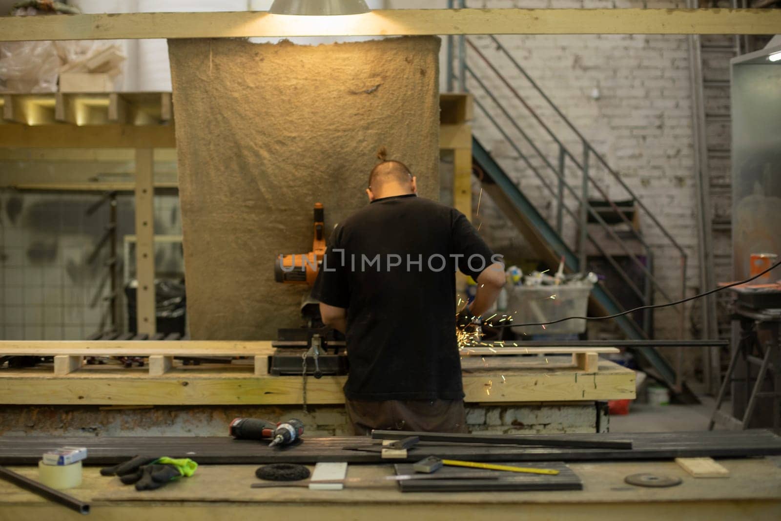 Worker in carpentry workshop. Production room. Guy at desk. Lots of tools in room.