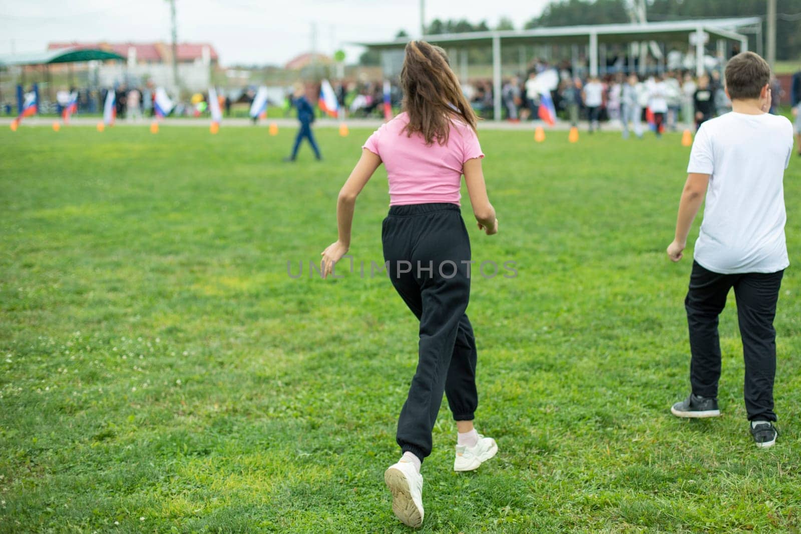 Child runs on lawn. Girl is running. Playing sports at stadium. Body training.