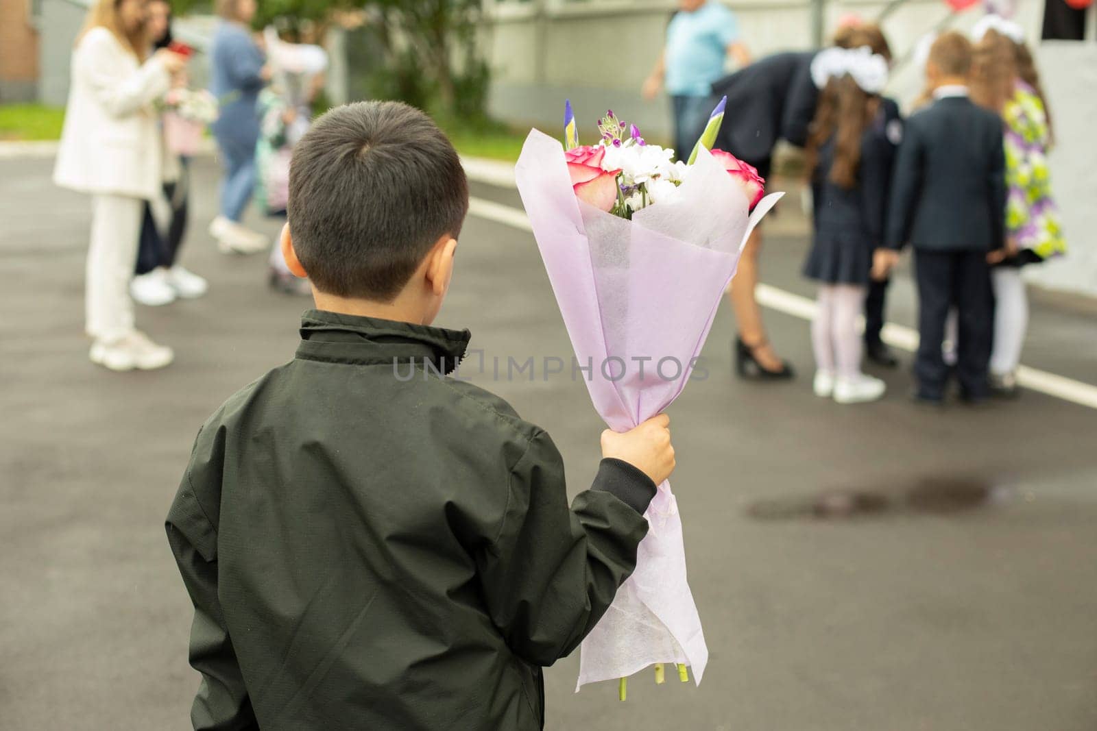 Child holds flowers. Schoolboy with bouquet for teacher. Boy at party. by OlegKopyov