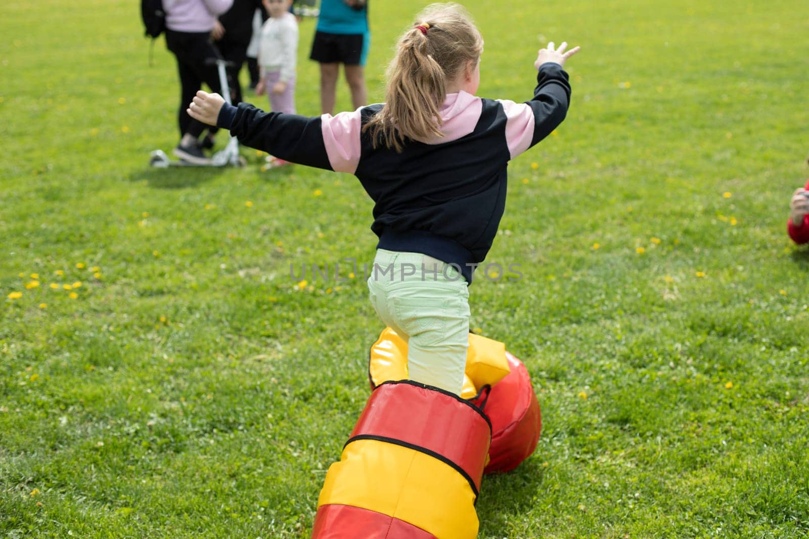 Child plays on green grass. Entertainment for children in park. Fun running contest. Funny shoes.