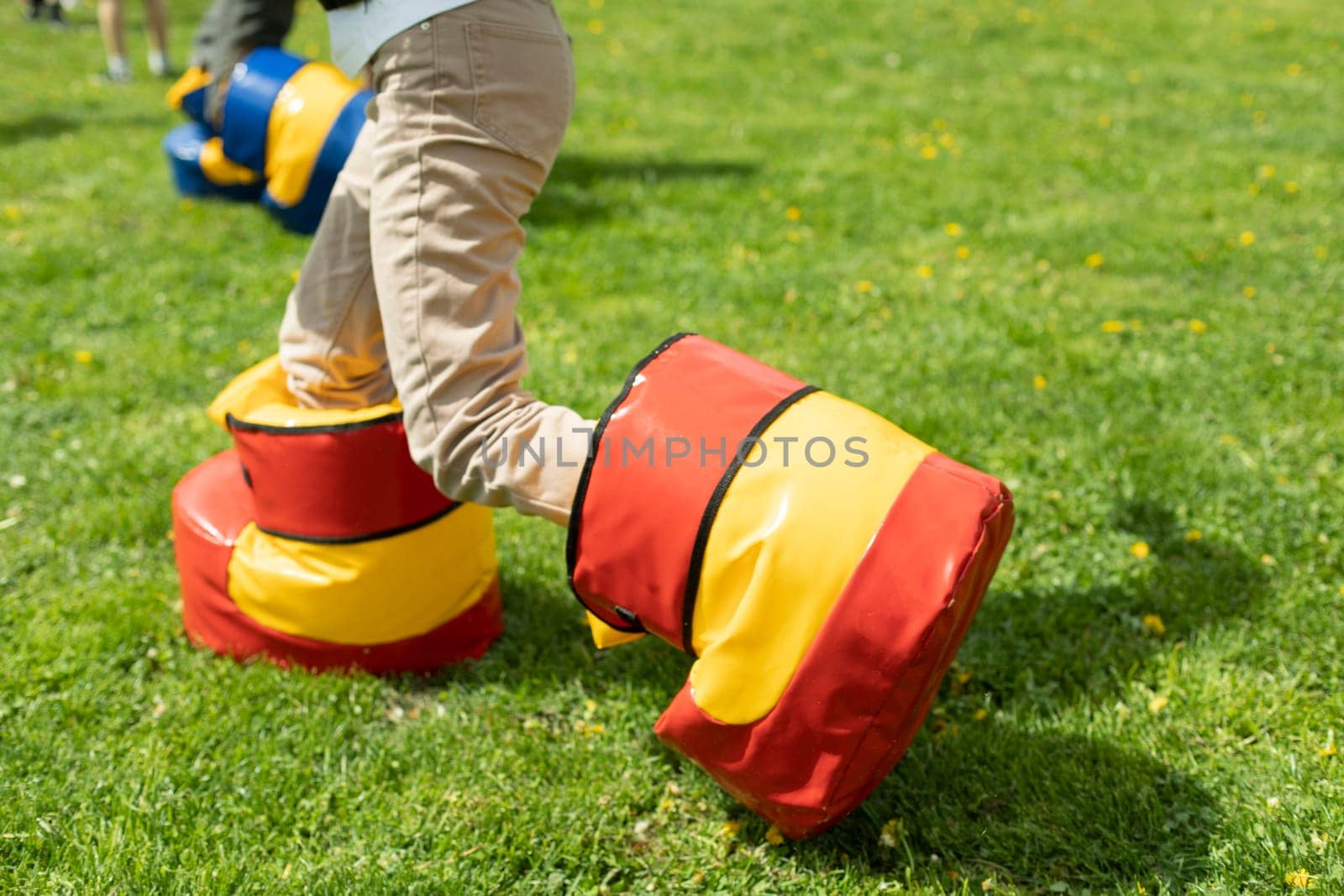 Funny shoes for game. Fun holiday of child in summer. Entertainment on green grass. Playing on lawn. Child in uncomfortable shoes.