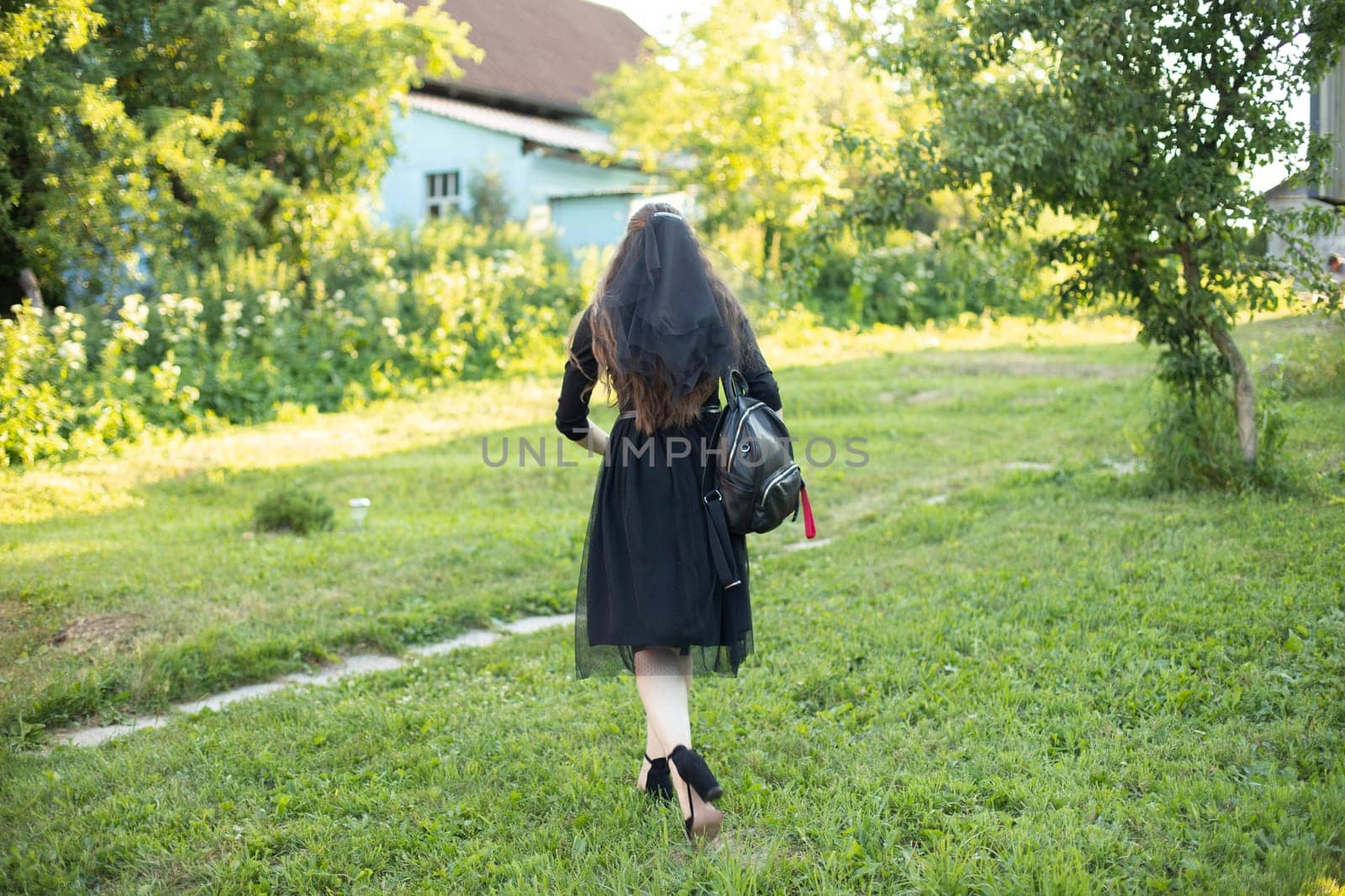 Girl in black dress stands alone on grass. Girl at party. by OlegKopyov