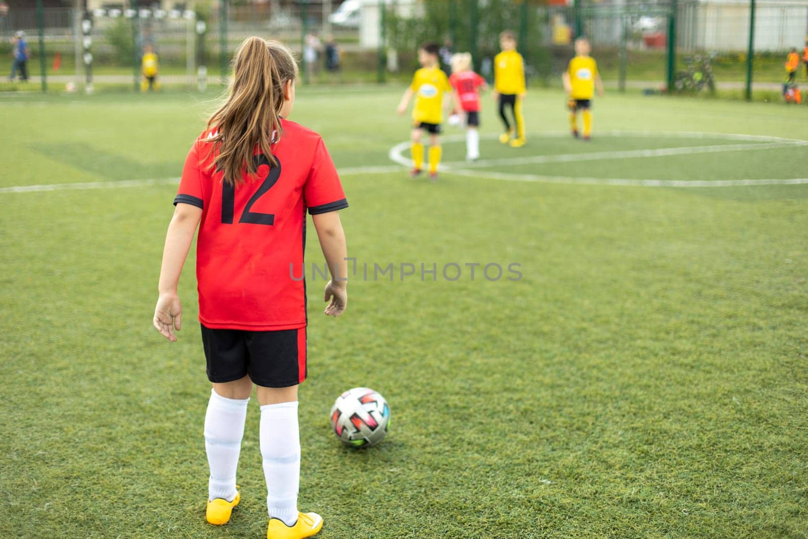 Girl plays football. Schoolgirl hits ball. Football match between children. Sports competition.