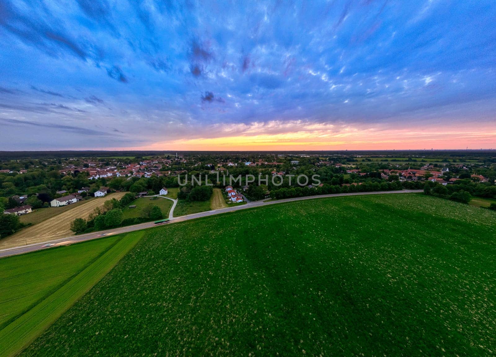 Sunset Glow Over Green Fields and Distant Town by AllesSuper