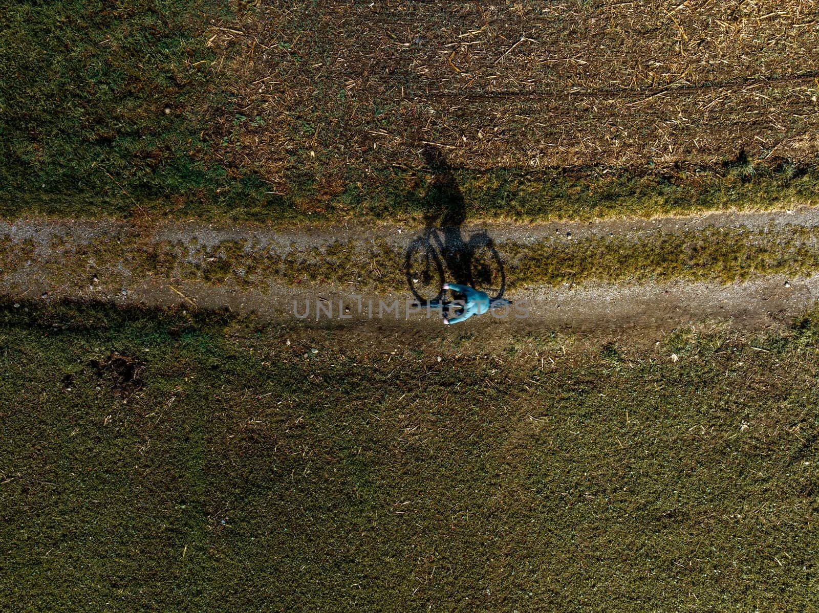 A man is riding his bike over a rural path, top down aerial view