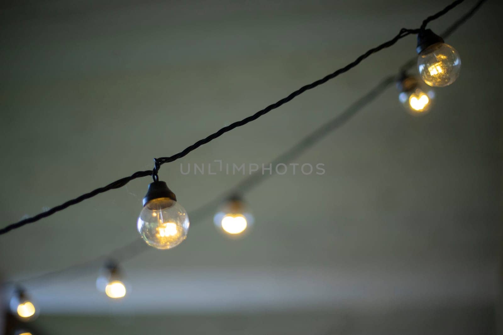 Light bulbs on wires. Garlands in interior. Incandescent lamp. Warm light.
