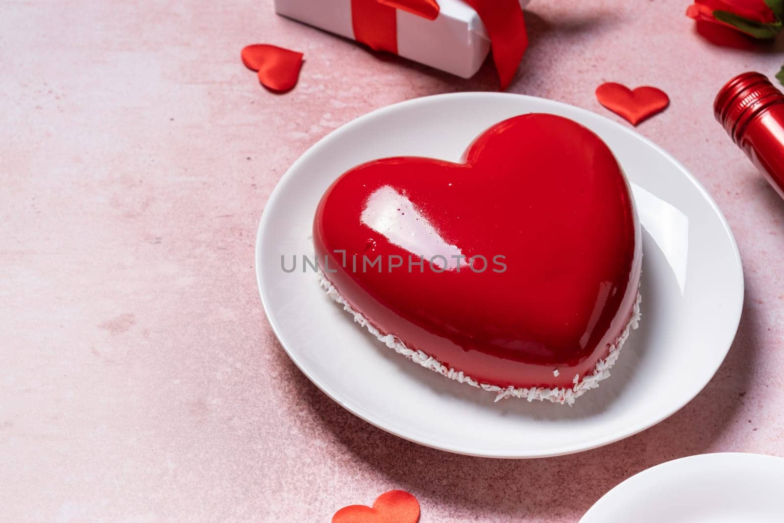 Valentines day. heart shaped glazed valentine cake, gift and wine on pink concrete background