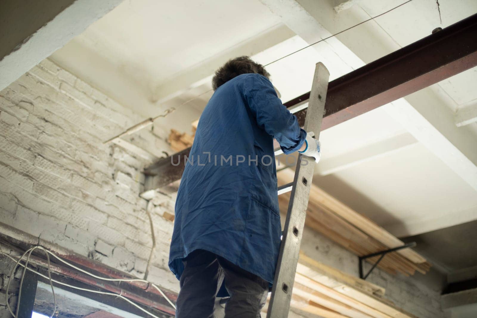 Guy is standing on stairs. Worker hangs chain on steel beam. Construction staircase. Man stands at height without insurance.