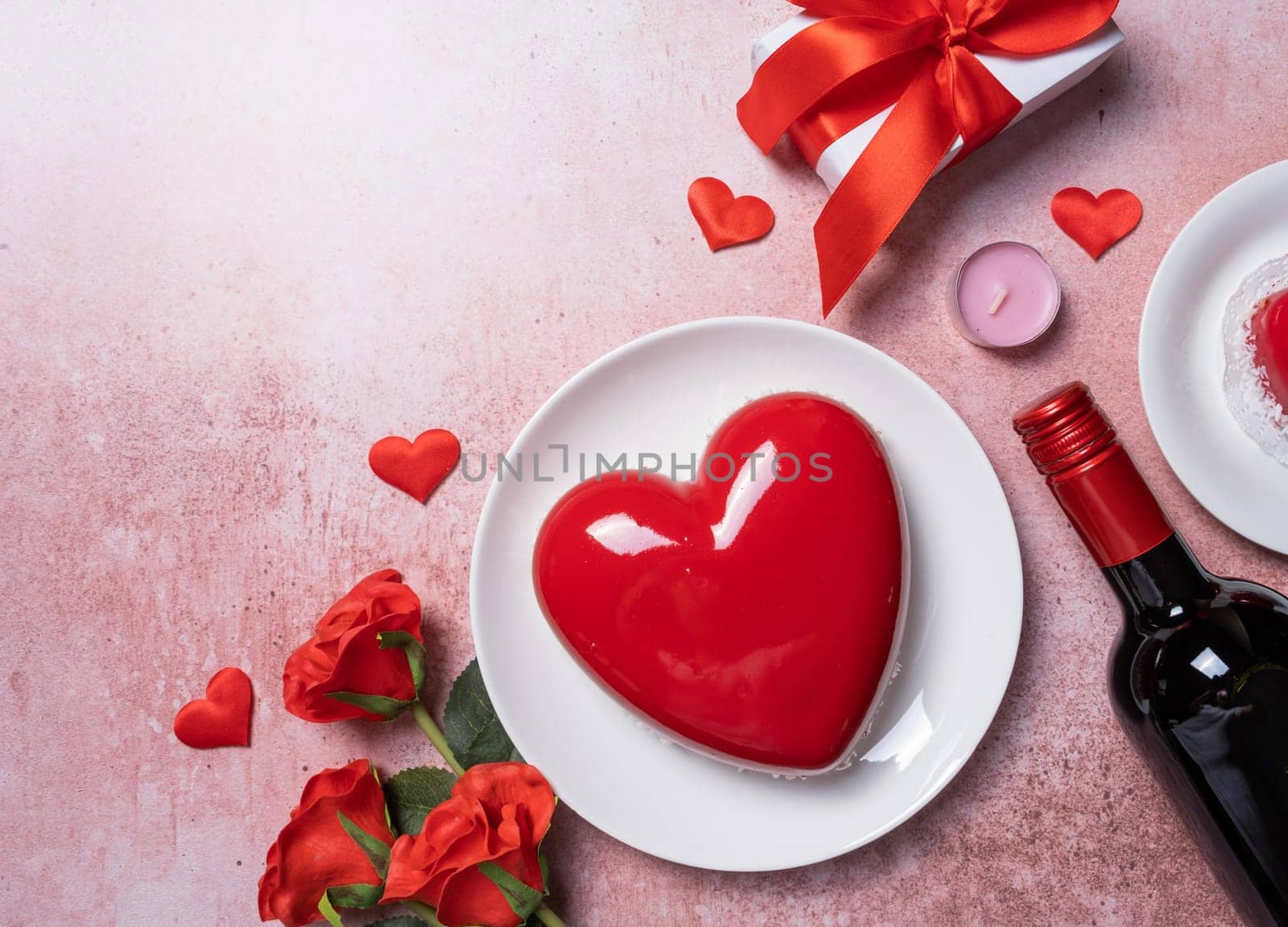 Valentines day. heart shaped glazed valentine cake, gift and wine on pink concrete background