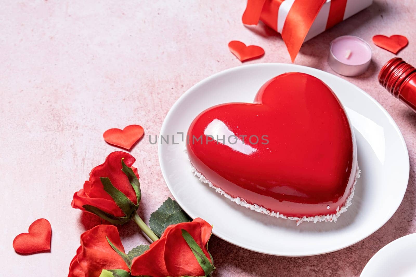 Valentines day. heart shaped glazed valentine cake, gift and wine on pink concrete background