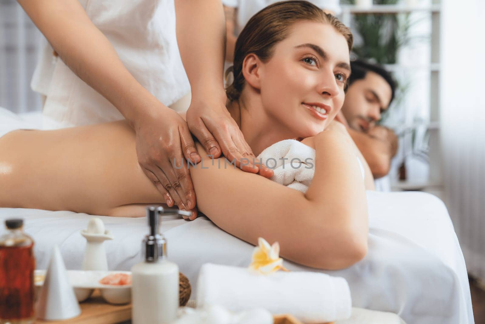 Caucasian couple customer enjoying relaxing anti-stress spa massage and pampering with beauty skin recreation leisure in day light ambient salon spa at luxury resort or hotel. Quiescent