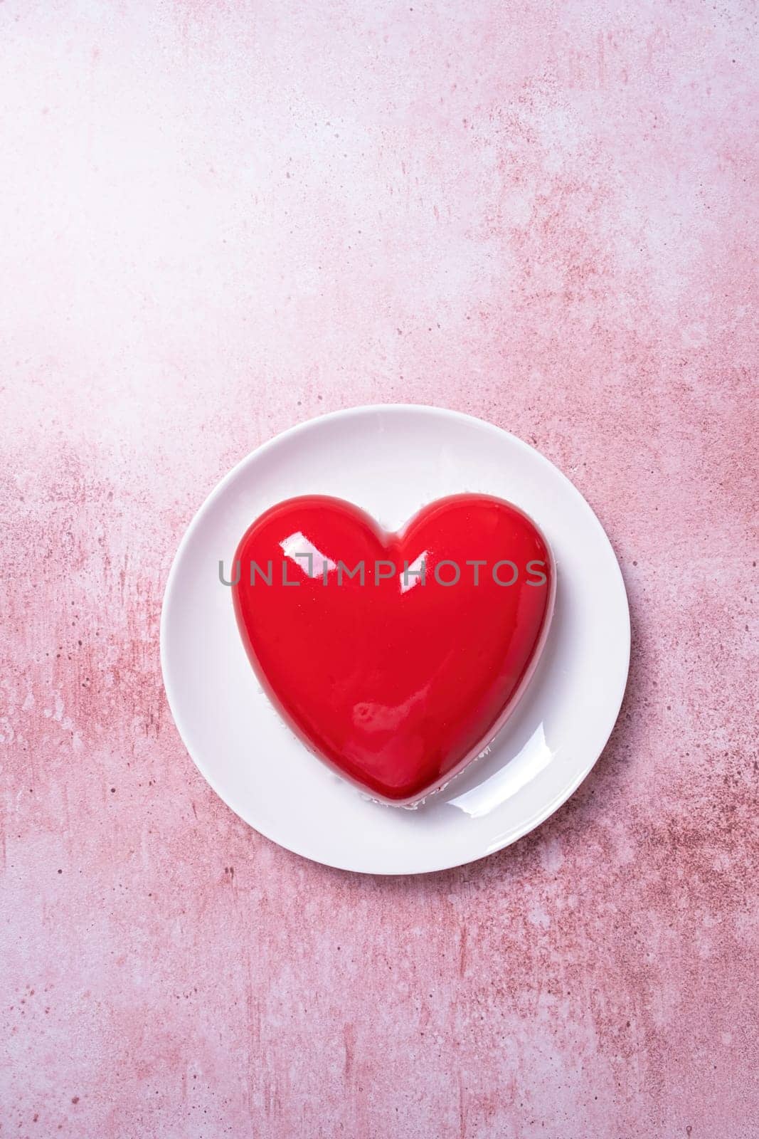 Valentines day. heart shaped glazed valentine cake on white plate on pink concrete