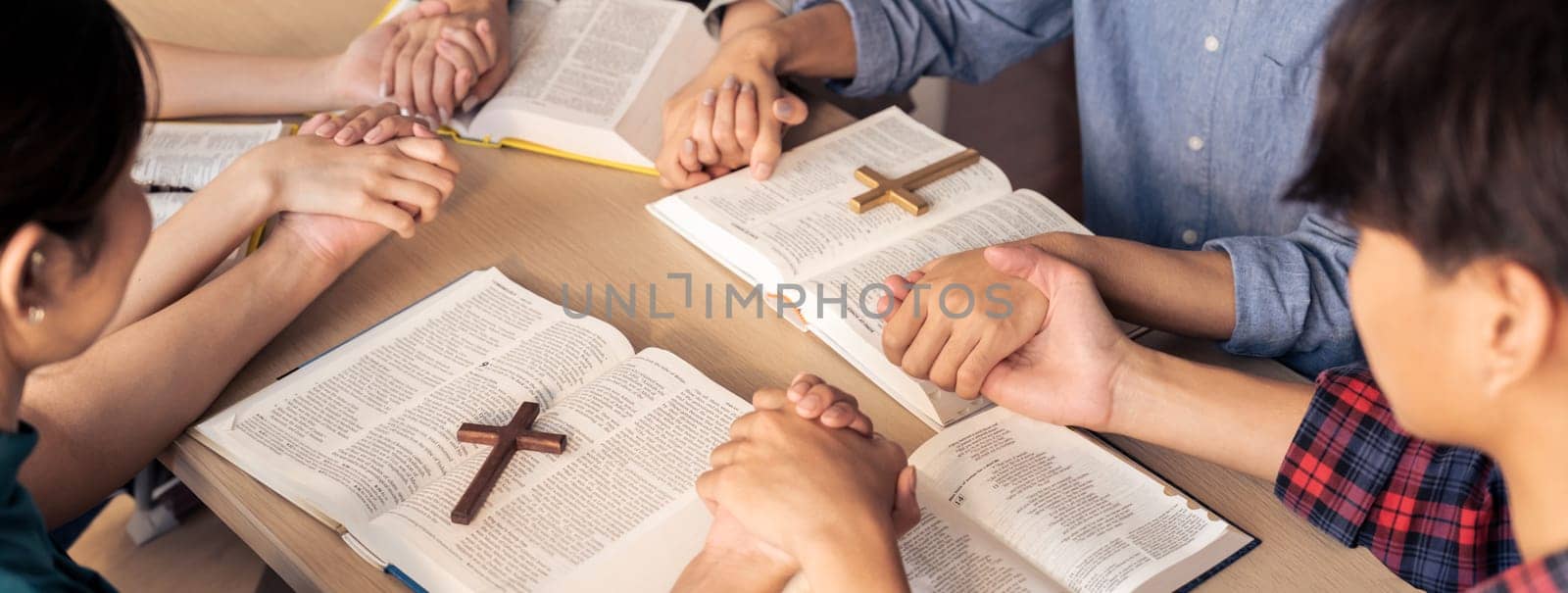 Cropped image of diversity people hand praying together at wooden church on bible book while hold hand together with believe. Concept of hope, religion, faith, god blessing concept. Burgeoning.