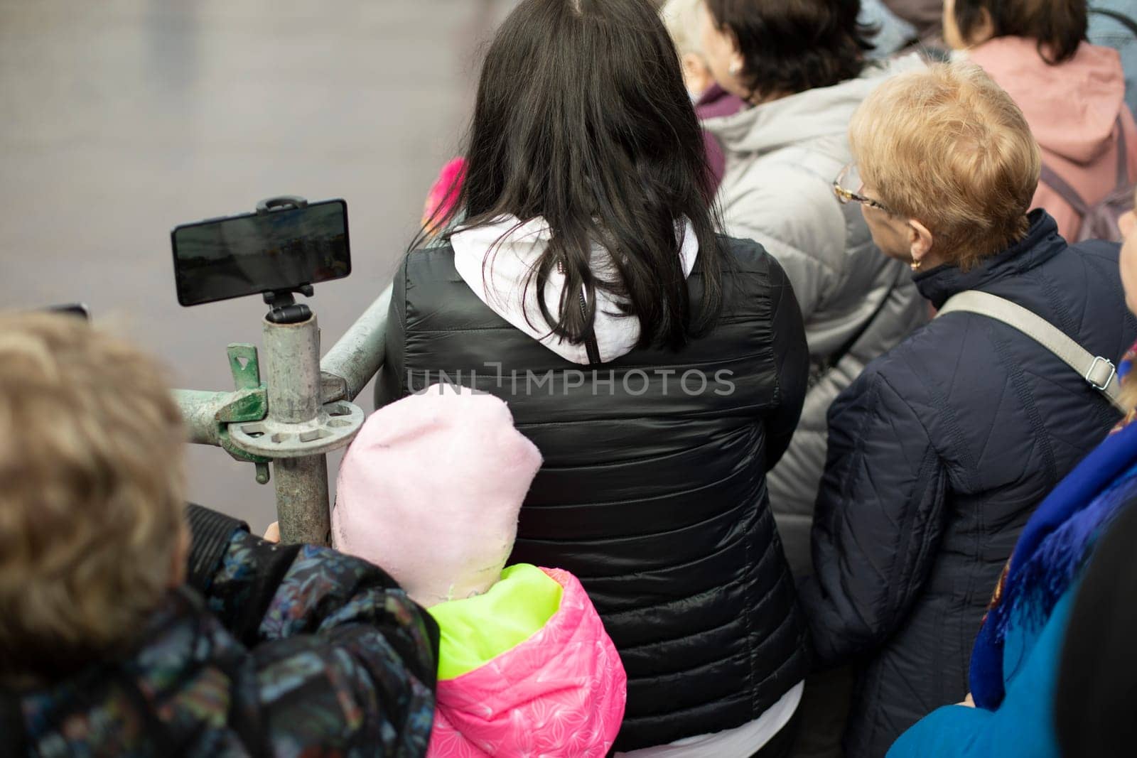 Lot of people watch show on street. People's backs. Street performance. by OlegKopyov