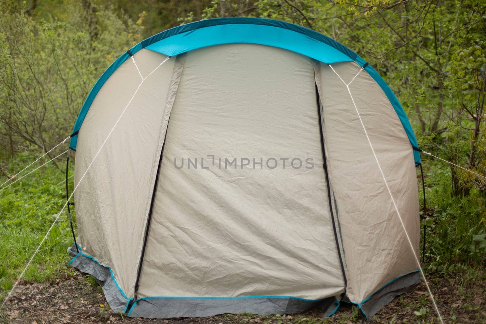 Tourist tent in forest. Tent for sleeping in nature. Equipment for going to park. Awning protects against rain.