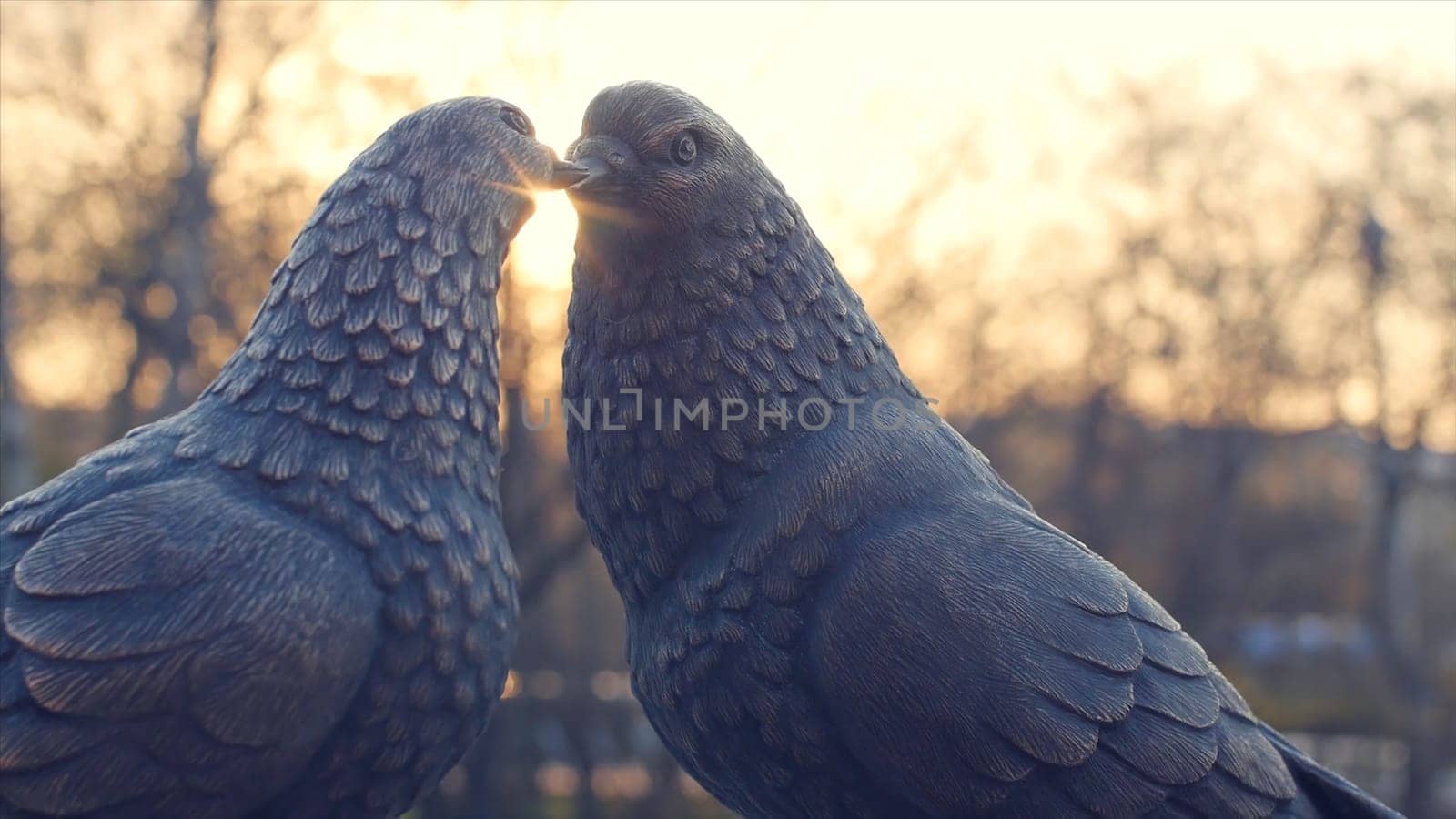 Pair of vintage white pigeon made of bronze and sun background. figurines pigeons made of metal. Two figurines of pigeons like a the monument of love. the monument of love made of bronze by Mediawhalestock