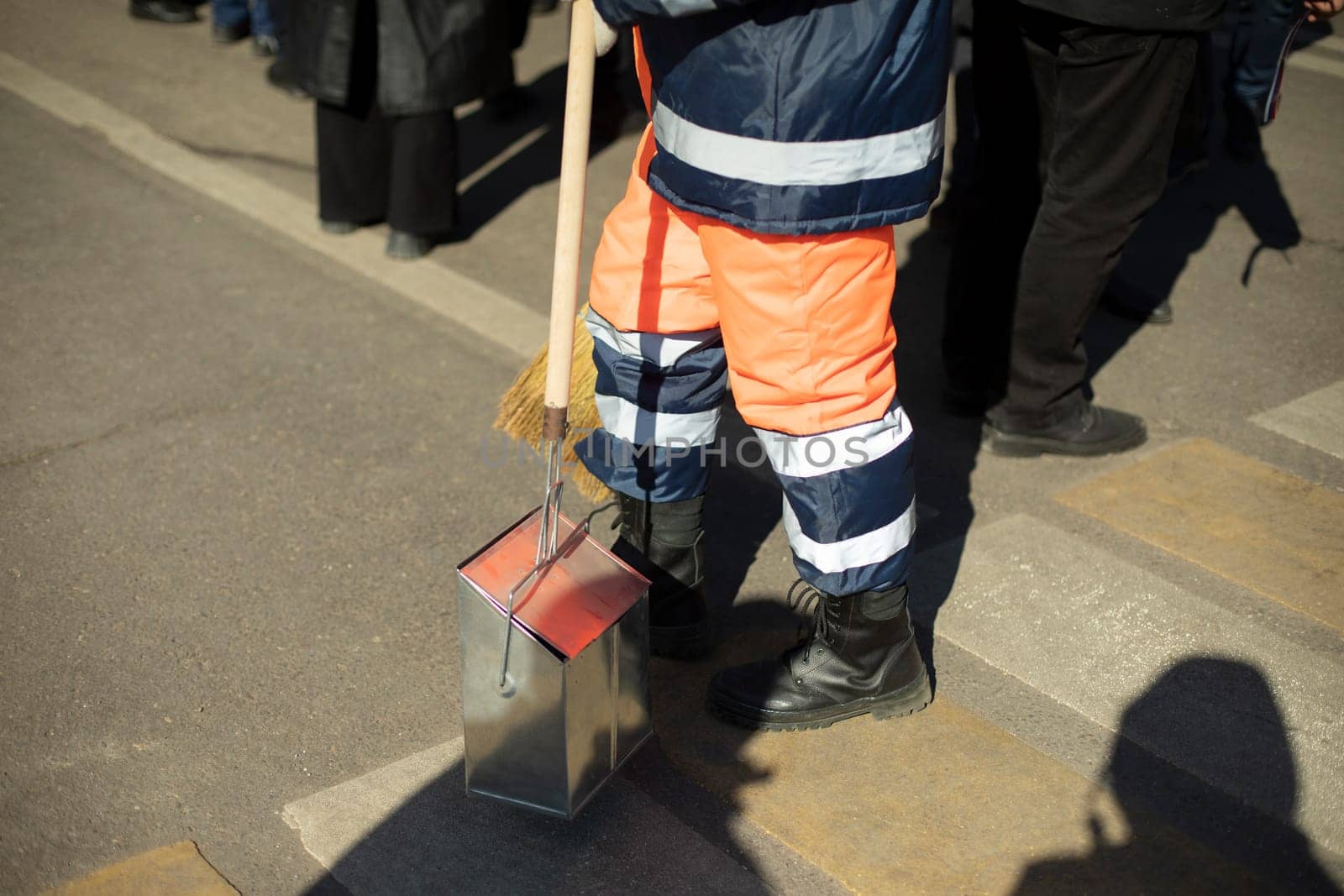 Janitor on street. Sweeping street. Garbage collection in city. Man in orange clothes.