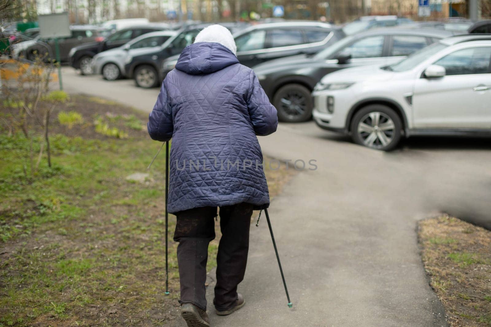 Woman with walking poles. Pensioner is engaged in race walking. Walk for health. Old woman does physical exercise.