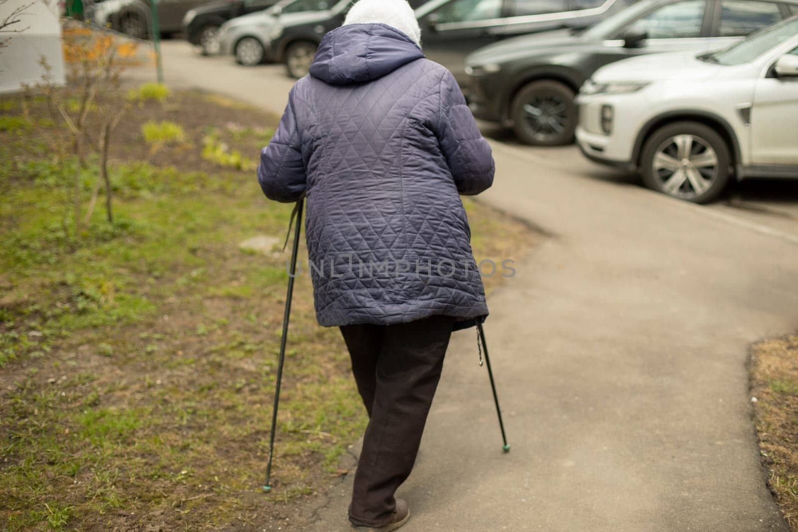 Woman with walking poles. Pensioner is engaged in race walking. Walk for health. Old woman does physical exercise.