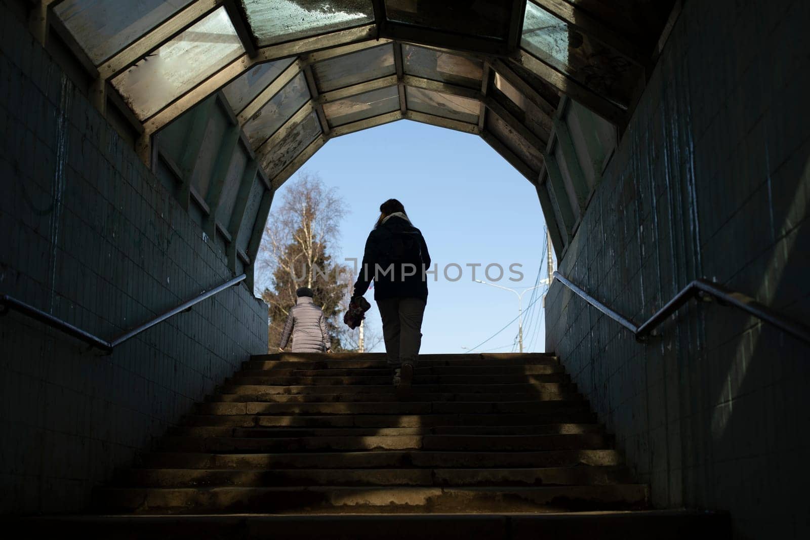 Man comes out of tunnel. Silhouette of girl walking down steps. by OlegKopyov