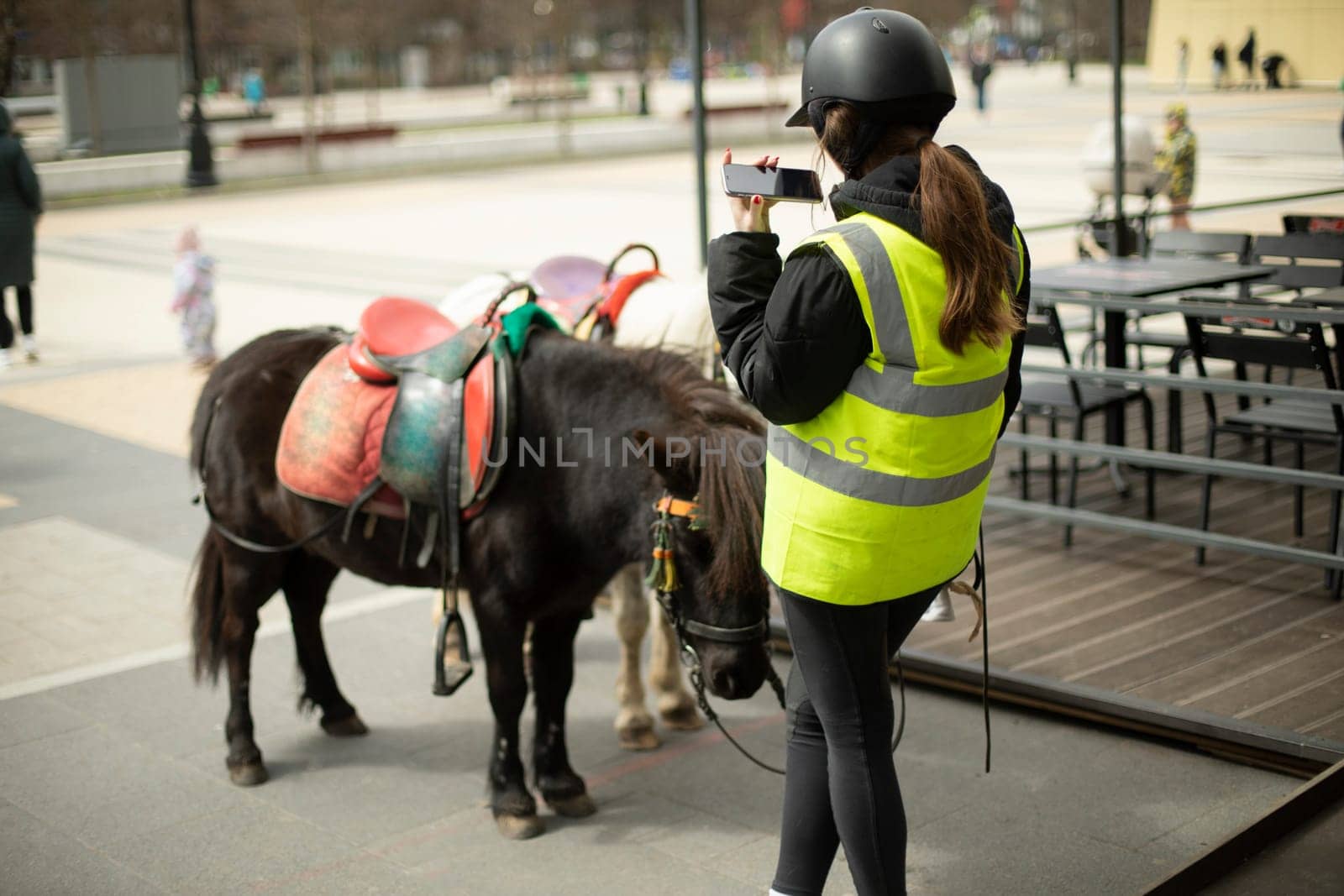 Girl with horse in town. Girl rides children on horse on street. Exploitation of ponies in metropolis. Rider walks animal.