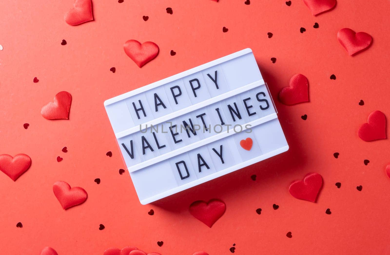 Valentines day. letter board with words Happy Valentines Day an heart shape confetti on red background