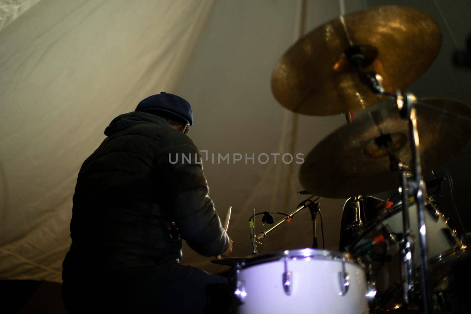 Drummer at music festival. African-American beats drums. Playing in group.