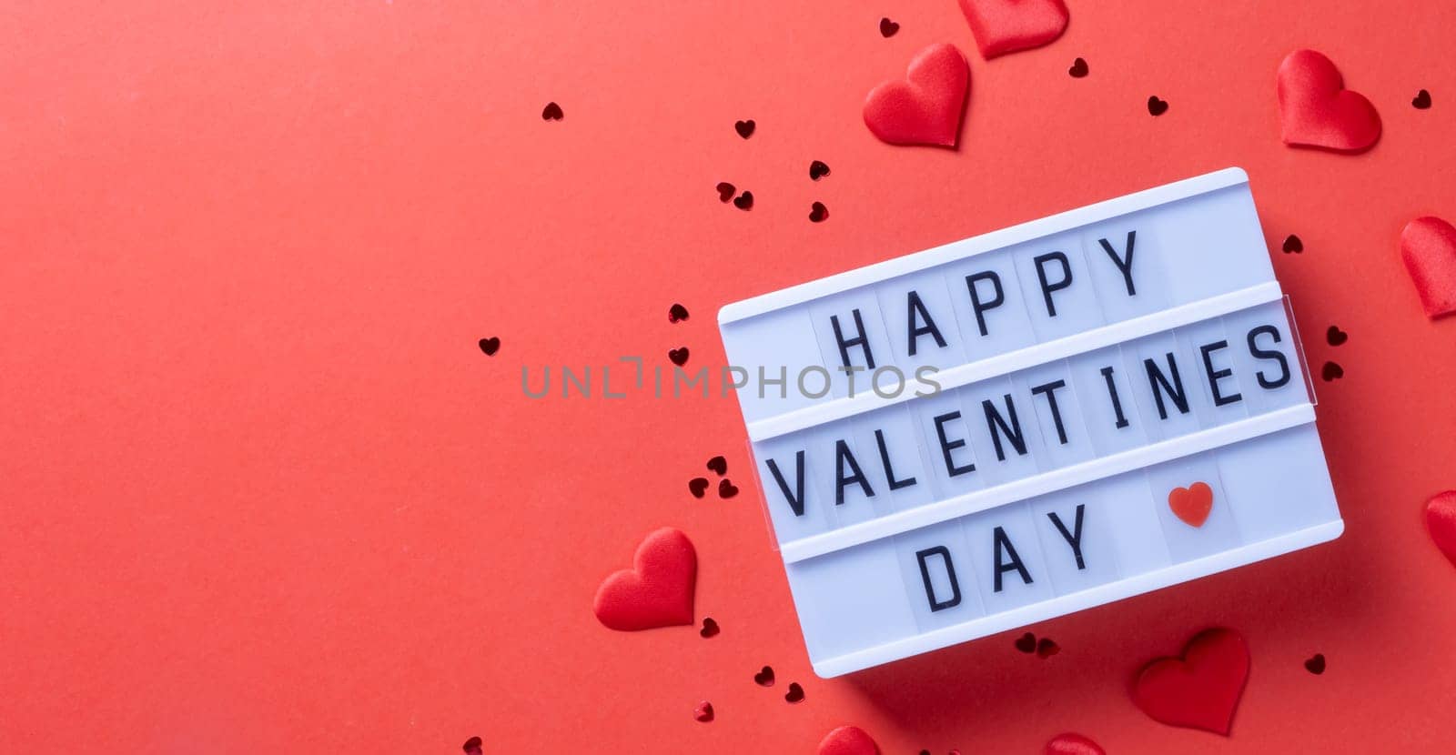 Valentines day. letter board with words Happy Valentines Day an heart shape confetti on red background