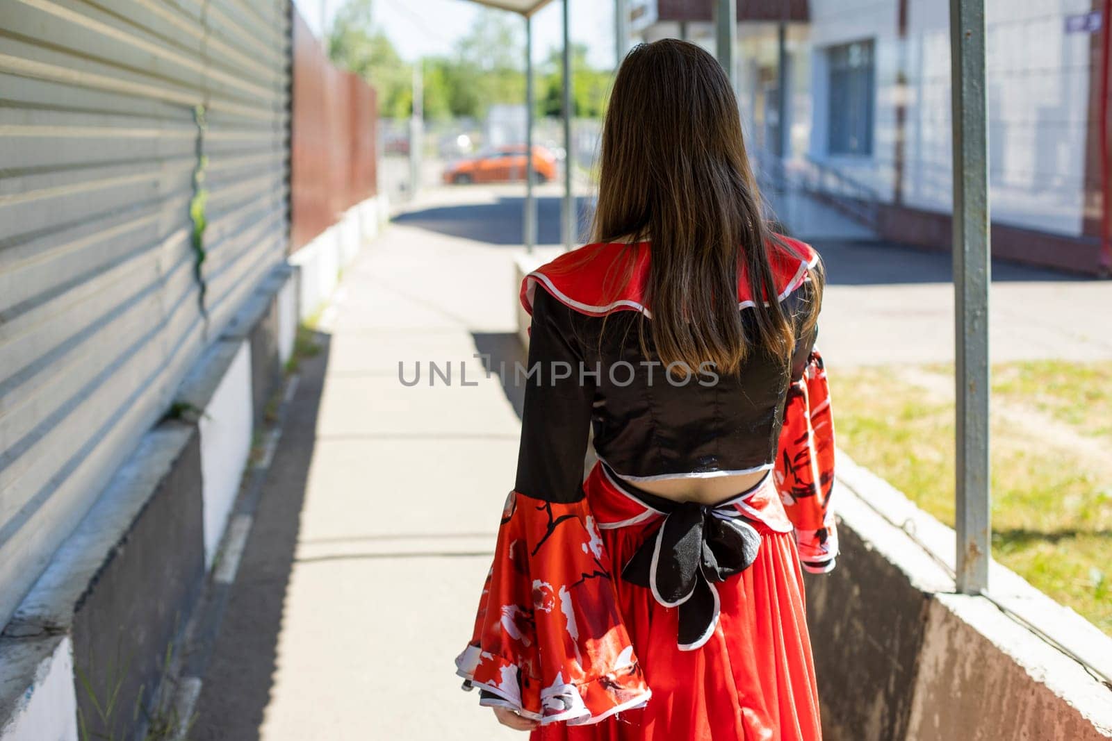 Girl in gypsy dress on street. Gypsy in town. Red dress. Folk costume.