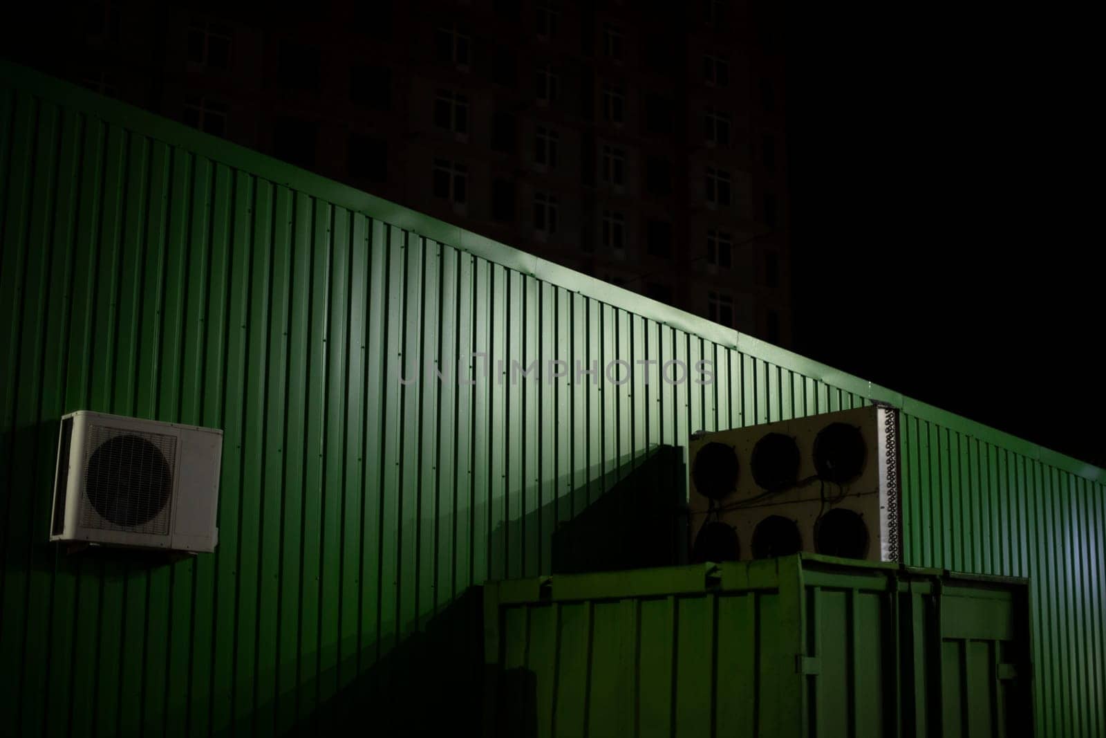 Warehouse building is in dark. Green wall at night. Store details. Technical structure.