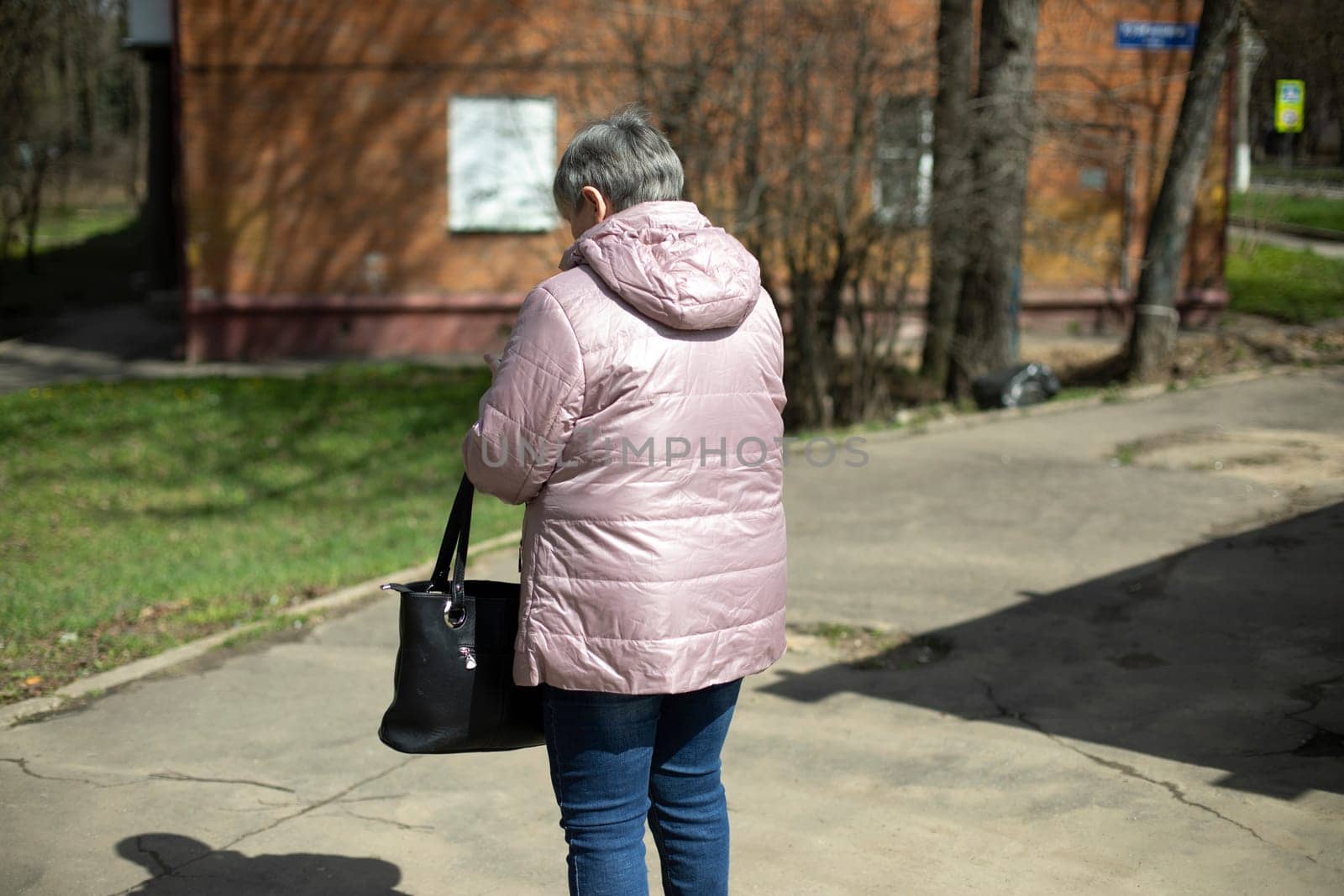 Woman in warm jacket in spring. Woman on street. Man from behind.